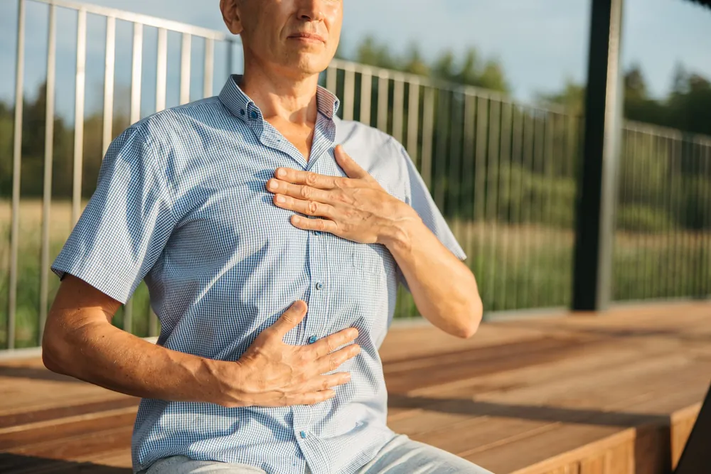 Man practicing a breathing exercise outdoors, representing respiratory care