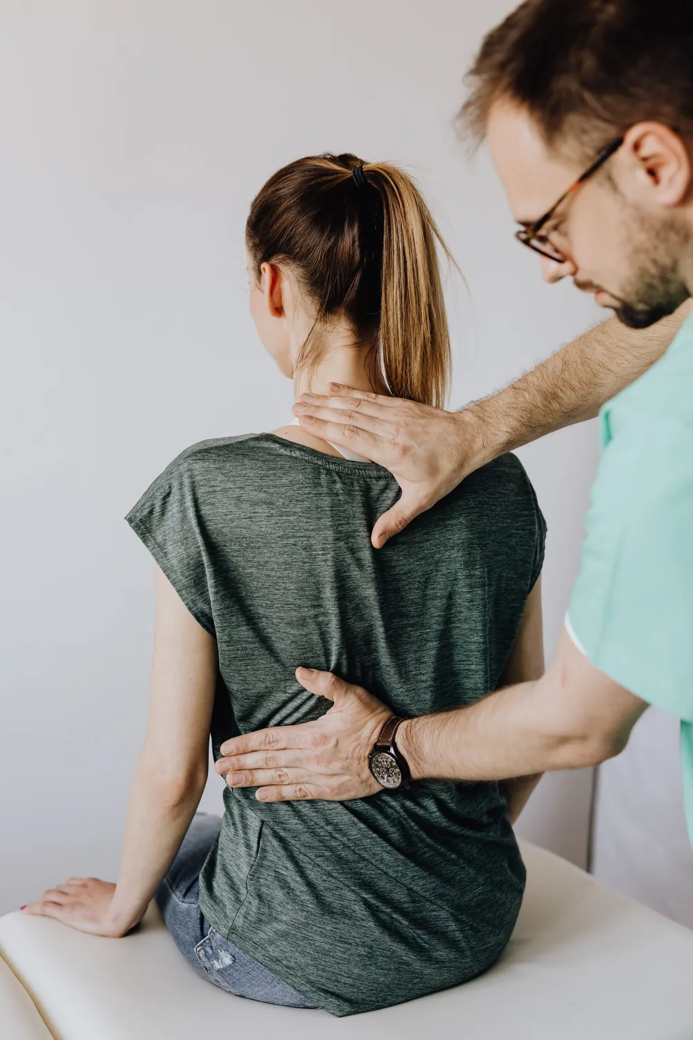 Physiotherapist examining a patient's back, representing spine and joint care